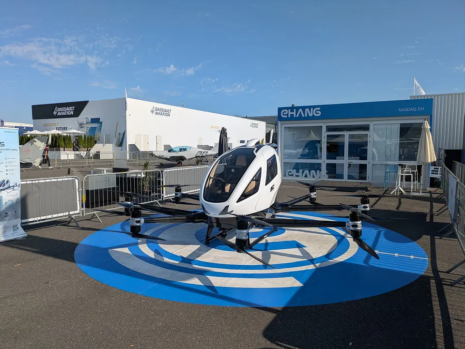 White two-seat EHang EH216-S multicopter on a blue landing pad outside an EHang chalet