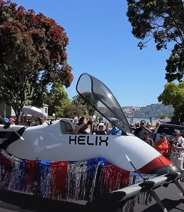White Pivotal Helix single-seat aircraft with HELIX lettering and a raised canopy, decorated with red, white and blue tinsel